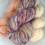 Pale peach and even paler apricot skeins along with a variegated purple and orange skein.