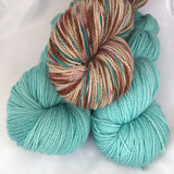 two skeins of aquamarine yarn with a skein of variegated browns and teal